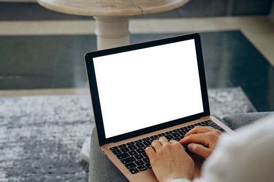 laptop mockup Person typing on a laptop with a blank white screen, suggesting remote work, online communication, writing and productivity in a casual home workspace or freelance
