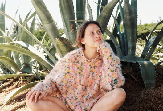 Woman Sitting Among Large Plants in a Colorful Sweater