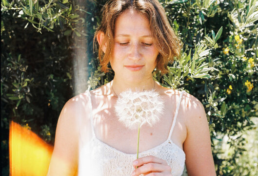 Woman Holds Dandelion Flower in Garden During Sunny Day