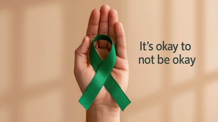 Fototapeta premium Awareness of mental health with a green ribbon held in hand for wellbeing support