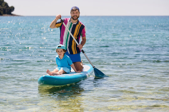 Father and Son Paddle Boarding on Clear Sea