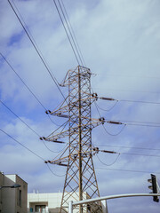 Stalowy słup wysokiego napięcia linii elektroenergetycznej na tle nieba z białymi chmurami © Szymon