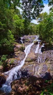 Scenic view of Ngao Waterfall, one of southern Thailand most beautiful waterfalls, flowing through dense green forest beneath the Khao Nom Sao mountain range in Ranong Province. high and wonder