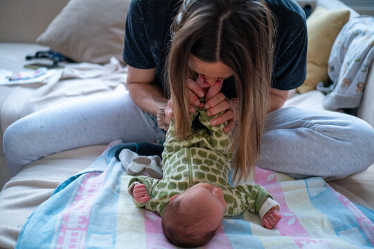 Mother smelling the feet of her newborn daughter 