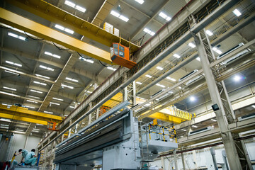 Fototapeta premium Industrial Factory Floor with Overhead Crane Systems and Manufacturing Equipment