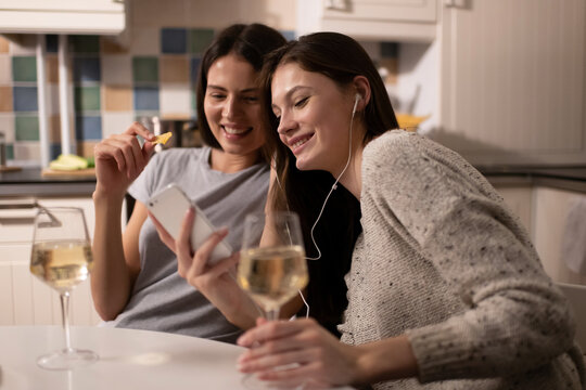 Young friends using smartphone and listening to music during party