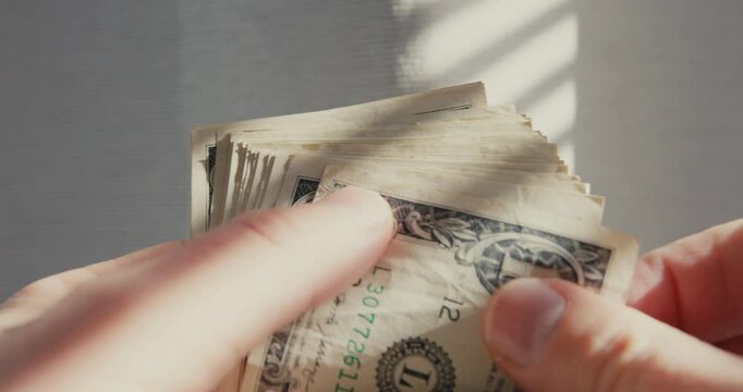 Close-up of hands counting one dollar bills
