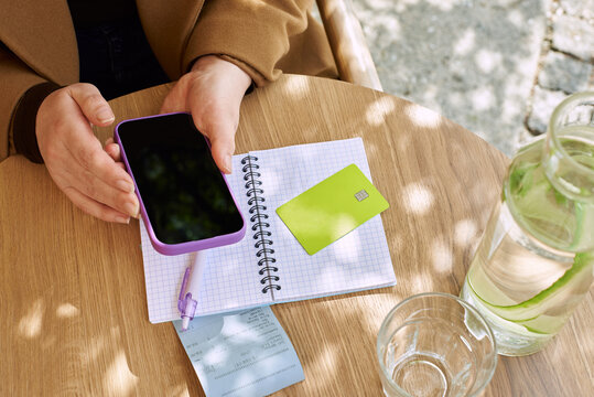 Person using phone and notebook at a table