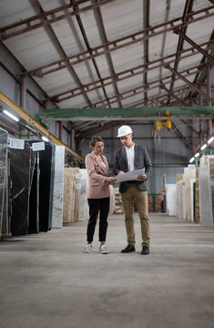 Male and female workers examining and discussing blueprints