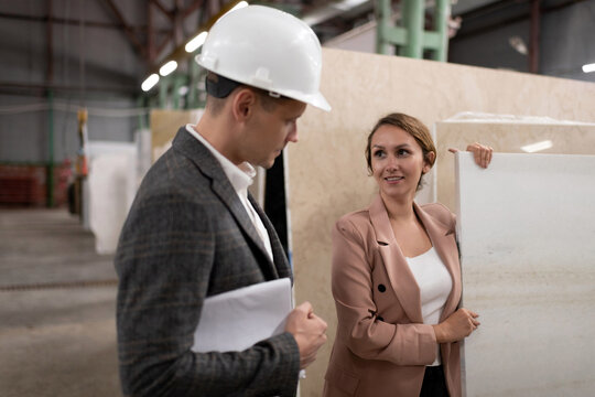 Adult female worker offering stone slab to architect