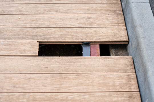 Damaged wooden decking with broken plank and visible gap in pedestrian walkway. 