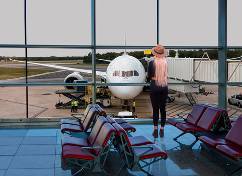Passenger airplane is parked on the taxiway of the international airport runway. View of the terminal's panoramic window - Cancun, Mexico