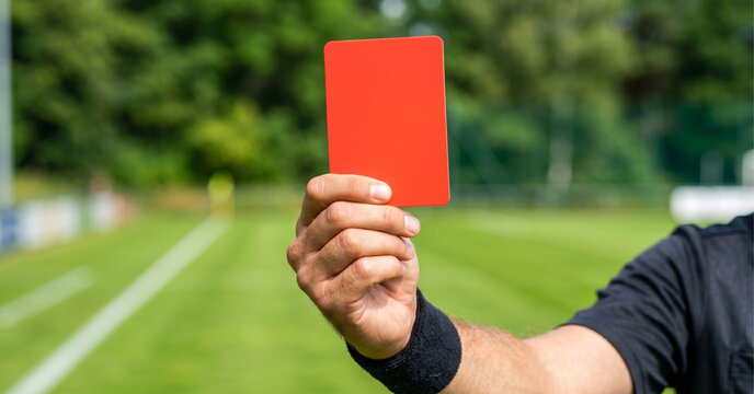 Close up of referee hand holding a red card on soccer field