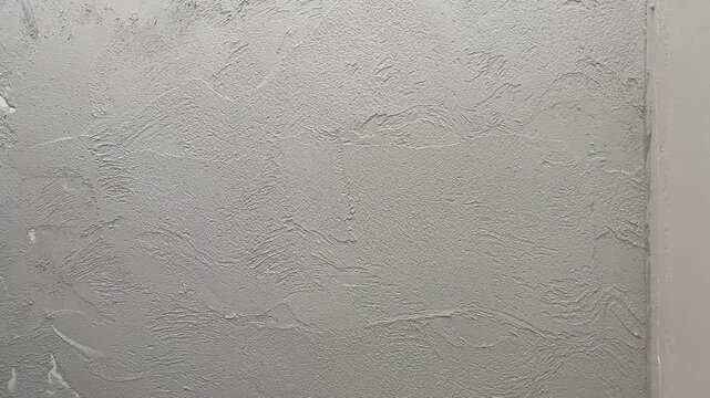 A person is applying plaster to a wall in a workshop. The process includes smoothing out the surface with a trowel. Steps are shown clearly for beginners.