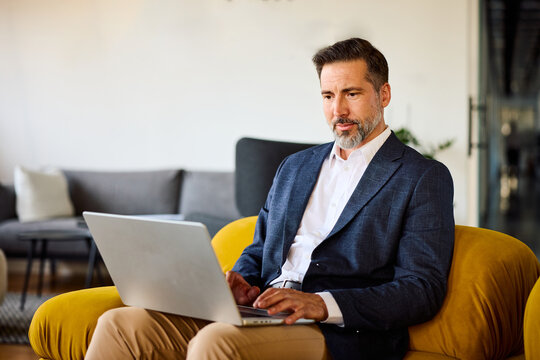 Businessman sits on the sofa, focused on his laptop