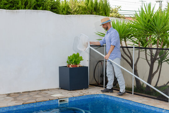 Pool maintenance worker inspecting and cleaning skimmer net