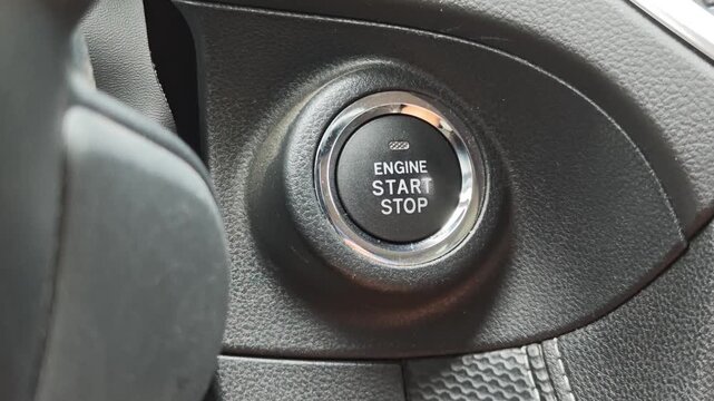 Close up of a finger pushing the engine start and stop button of a modern car. Ignition and keyless entry system for driver convenience