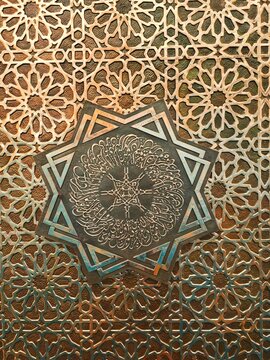 Detailed Arabic calligraphy carving in the shape of an eight-pointed star on a metal door or mosque wall.