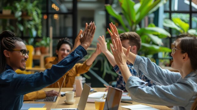 Colleagues celebrate their professional success with a high five during a collaborative office meeting.