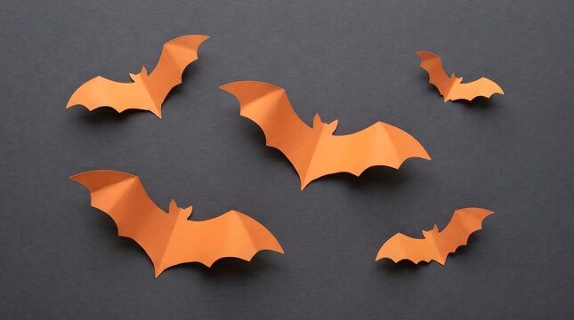 Orange paper bats flying on a dark gray background for halloween decorations
