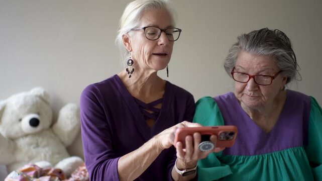 Mature daughter visits her elderly mother at the senior care facility to share stories and look through photos together