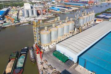 Aerial view of riverside industrial port with grain silos and cargo barges © PhamHong