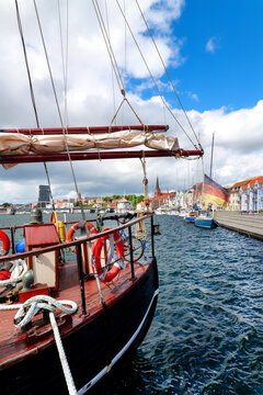 Historic sailing vessel with German flag in the harbor of Sonderborg beneath a blue summer sky overlooking the waterfront promenade. Denmark