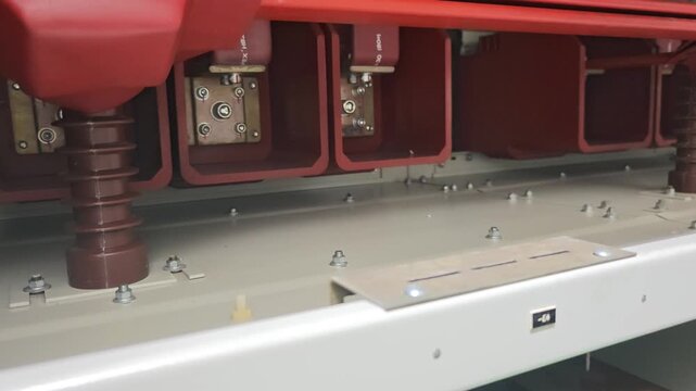 Close up video of red insulators and copper connections inside a medium voltage container switchgear for industrial power distribution.