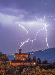 Fototapeta premium 14th-century medieval castle captured during a severe thunderstorm with intense electrical activity, Castellar, Saluzzo, Bronda Valley, Piedmont, Italy. 