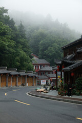 Fototapeta premium Traditional Chinese Buildings in Wudang Mountains with Misty Forest and Mountain Road