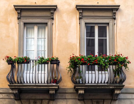 A close-up of two windows with flower-filled balconies on a beige building