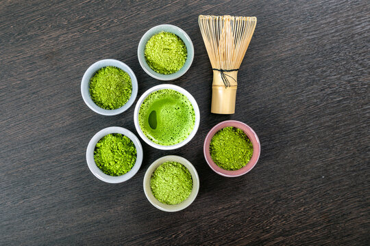 Matcha powder of various varieties in small cups with bamboo whisks and the finished drink. Traditional Japanese tea ceremony accessories with organic green
