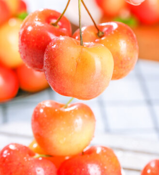 Fresh Golden Rainier Cherries with Water Droplets on White Wood Background