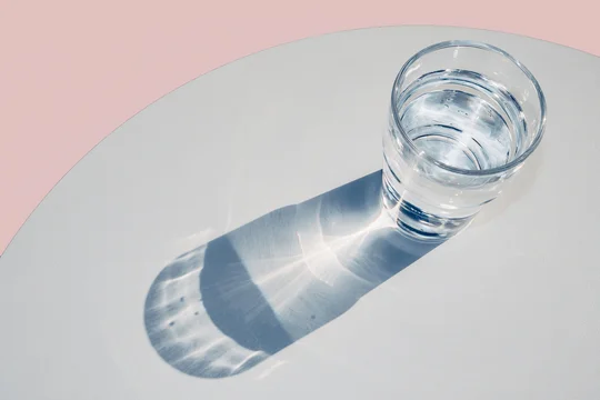 Glass of water casting strong shadows and natural caustic light patterns