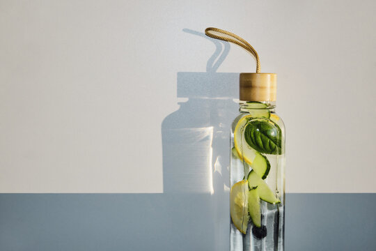 Reusable glass bottle filled with revitalizing fruit and herb infused water for healthy hydration