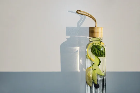Reusable glass bottle filled with revitalizing fruit and herb infused water for healthy hydration