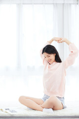 Naklejka premium Relaxed young woman stretching on rug at home in bright morning light