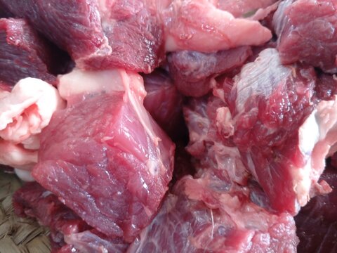 Raw red meat chunks on woven surface