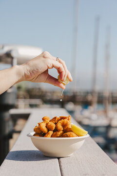 Hand Squeezing Lemon on Popcorn Shrimp