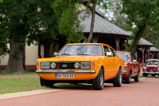 Ford Taunus GT TC1 Coupe 1970s - vintage orange car parked near a historic wooden pavilion building during an 30th oldtimer festival in Palic, Serbia on July 5, 2026.