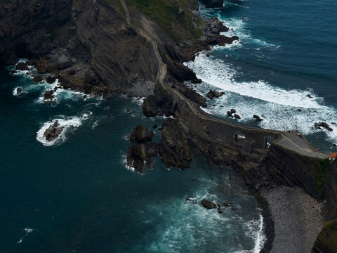 winding pathway along rocky cliffs by ocean with rugged and adventurous atmosphere. aerial perspective highlights natural beauty and adventure in travel and outdoor settings.