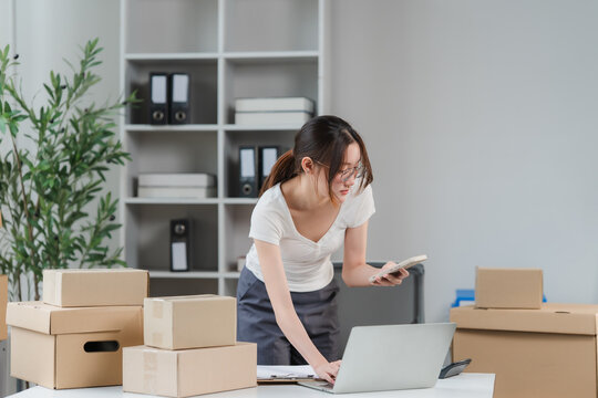 Small Business Owner at Work: A young woman, likely an entrepreneur, is diligently managing her online store, surrounded by packages and working on her laptop.