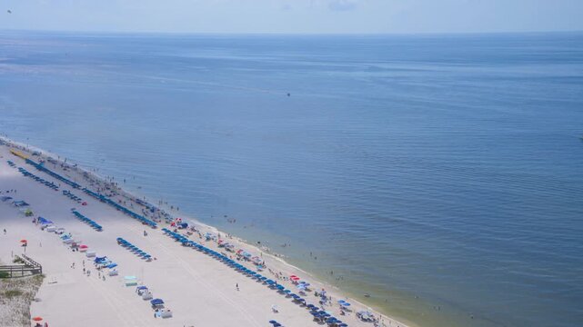 Stunning aerial view of the white sand beach in Orange Beach / Gulf Shores, Alabama during summer. Colorful umbrellas and chairs line the shore along the turquoise Gulf of Mexico / America waters