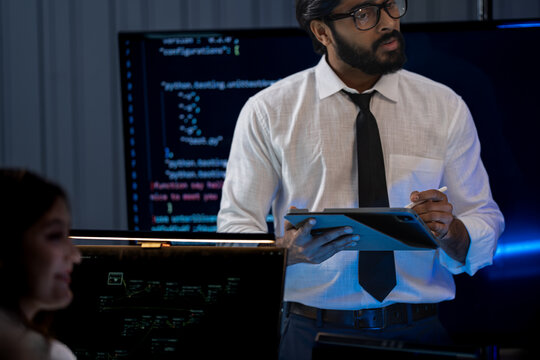 South Asian male and Black female professionals celebrate achievements in a dark tech office holding a certificate of recognition.