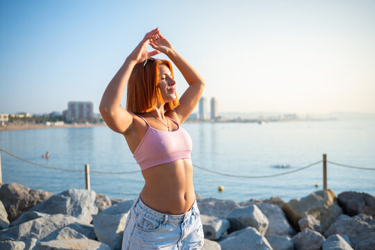 Redhead woman stretching enjoying sunny fitness by the sea