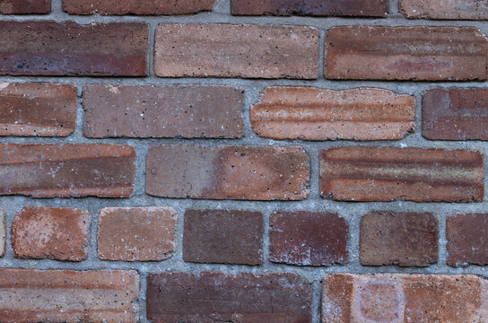 Background of new red bricks in a wall with grey mortar