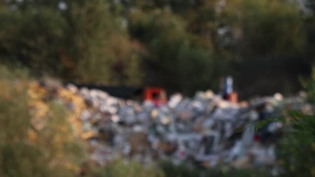 Wide shot of large landfill with machinery moving waste and dust. This video is suitable for documentaries on waste management, environmental impact, or industrial operations.