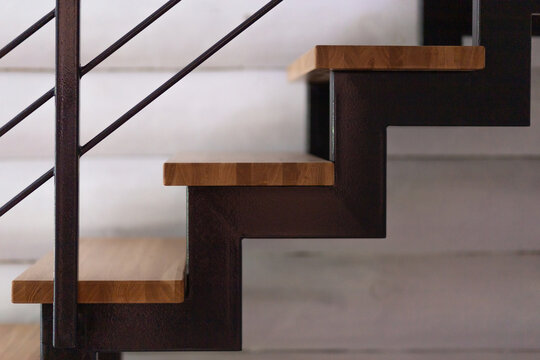 Wooden stairs with black railing inside a modern home, interior architecture, compact living space, clean geometric design, home detail.