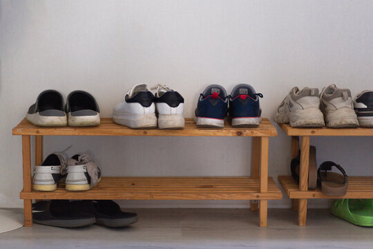Shoes arranged on a wooden rack in a home entryway, organized storage, everyday lifestyle, tidy household, casual footwear display.