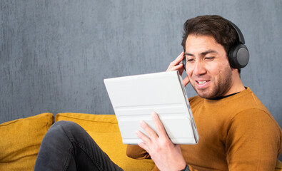 Young man enjoying digital content on a tablet with headphones © Diego D